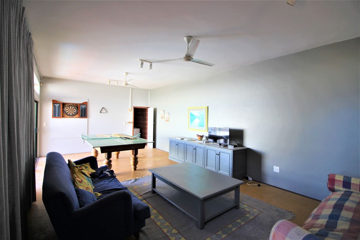 Spacious living area featuring ceiling fans, tiled flooring, and direct access to an adjacent utility space.