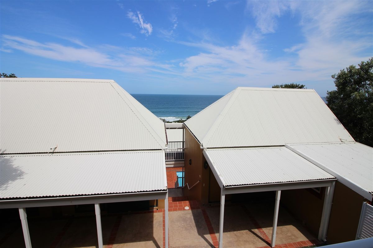 Elevated view overlooking the property's rear courtyard, patio areas, and swimming pool, with a clear horizon view of the ocean.
