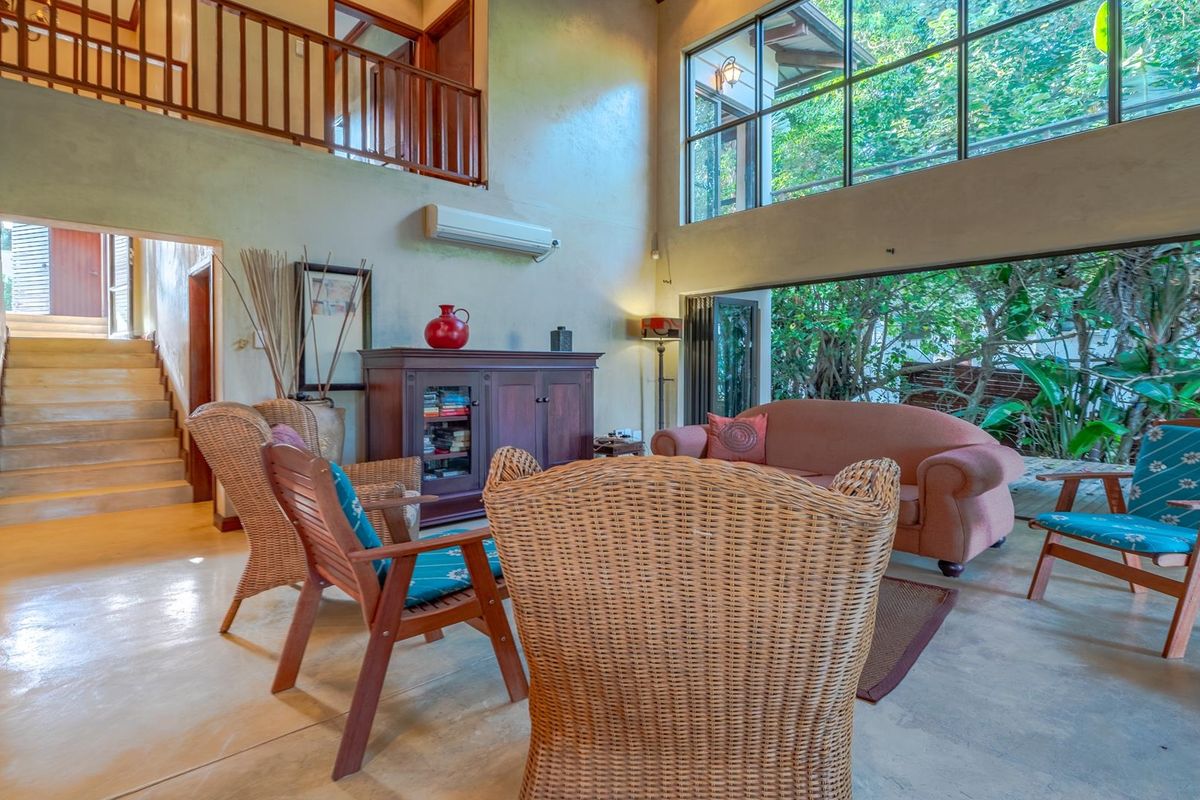 Spacious double-volume living area featuring polished concrete floors, a mezzanine level, and expansive windows overlooking lush greenery.