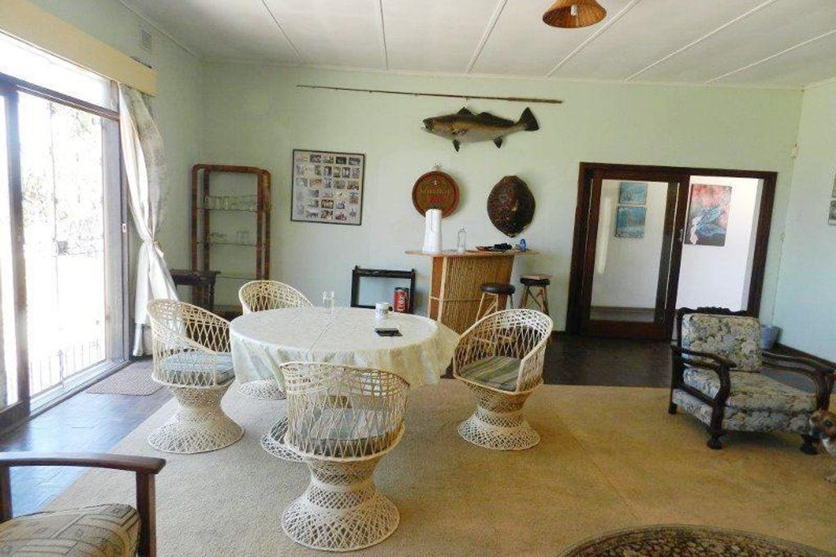 Spacious living area featuring large sliding glass doors, carpeted flooring, and a neutral color palette, offering a versatile space for relaxation and dining.