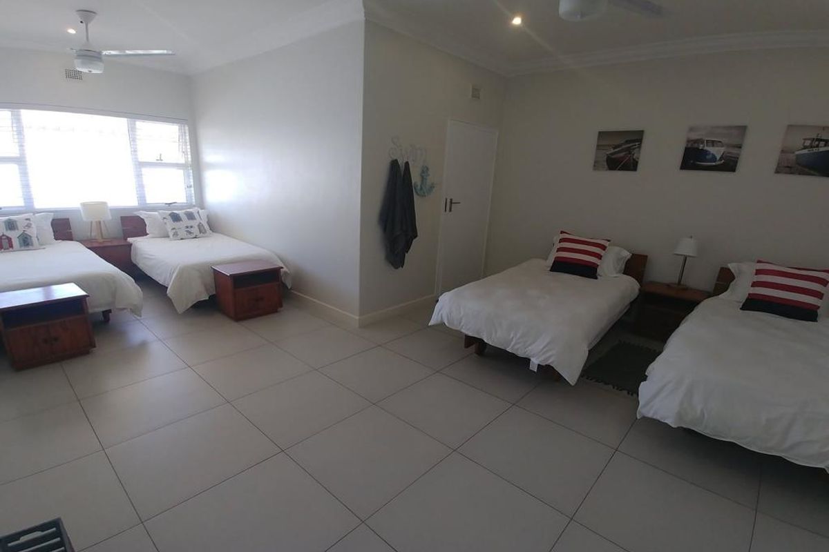 Spacious bedroom featuring large format floor tiles, recessed downlighting, and ceiling fans, providing a clean and functional living space.