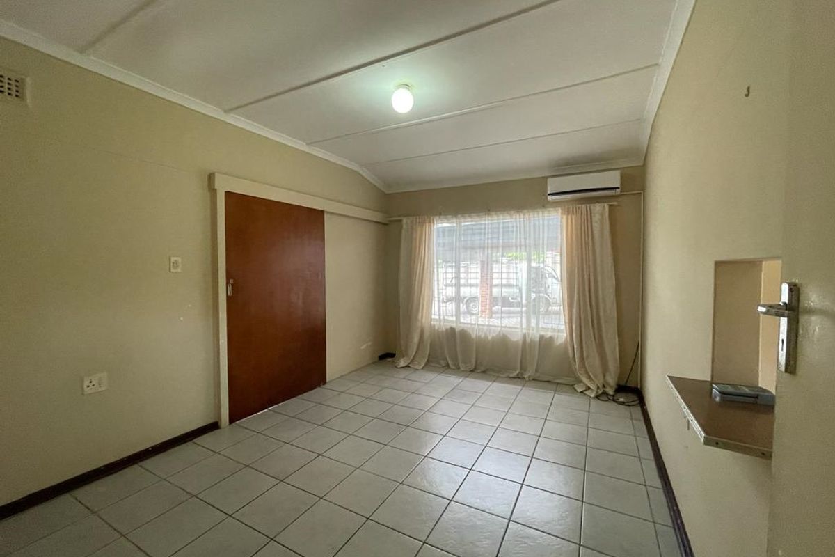 A functional bedroom featuring tiled flooring, a built-in sliding door, and a wall-mounted air conditioning unit.