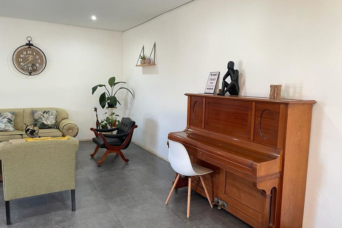 A spacious living area featuring large format grey floor tiles and neutral wall finishes, providing a versatile and open living space.