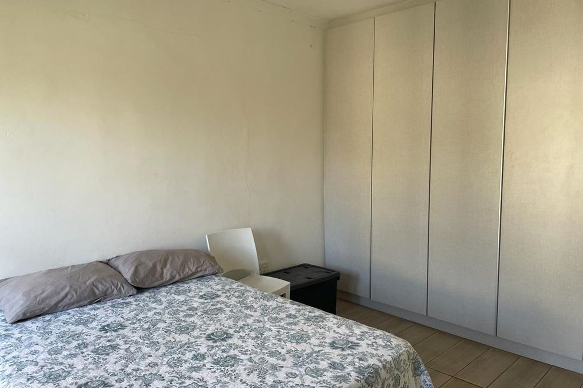A bedroom featuring built-in floor-to-ceiling wardrobes and tiled flooring.