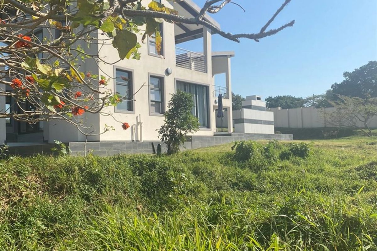 A view of the rear elevation of a multi-story residential property featuring a patio area and landscaped garden space.