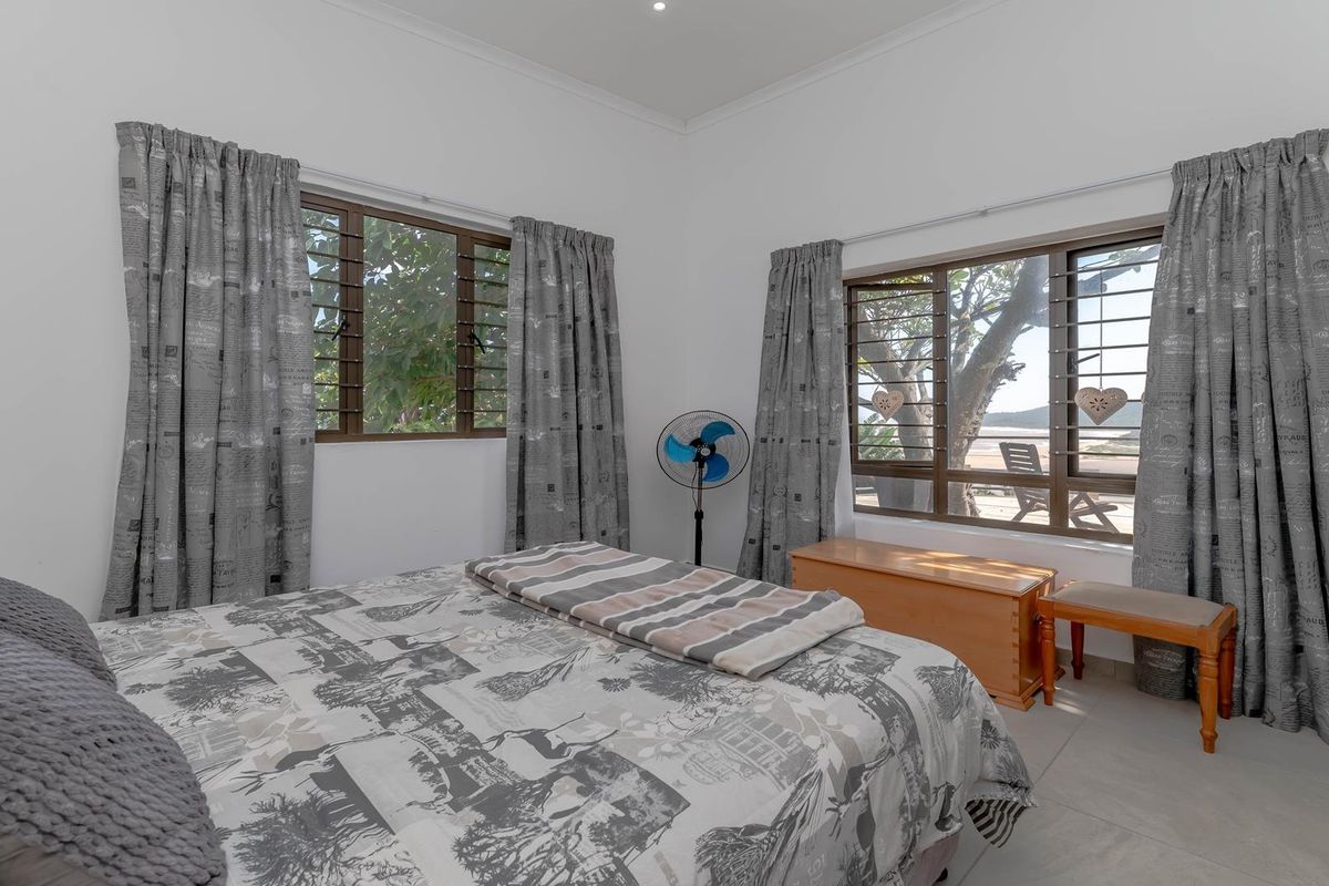 A bright bedroom featuring large windows with views, tiled flooring, and built-in wardrobe storage.