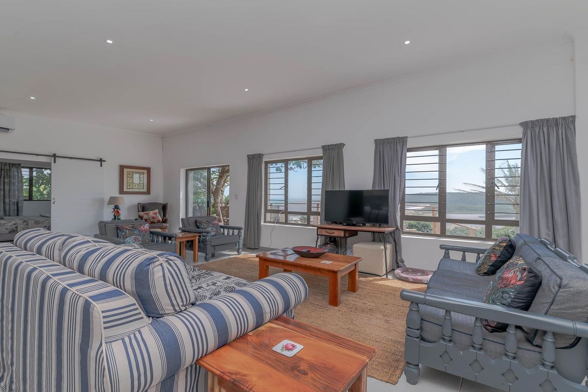 Spacious open-plan living area featuring large windows with scenic views, recessed ceiling lighting, and a wall-mounted air conditioning unit.
