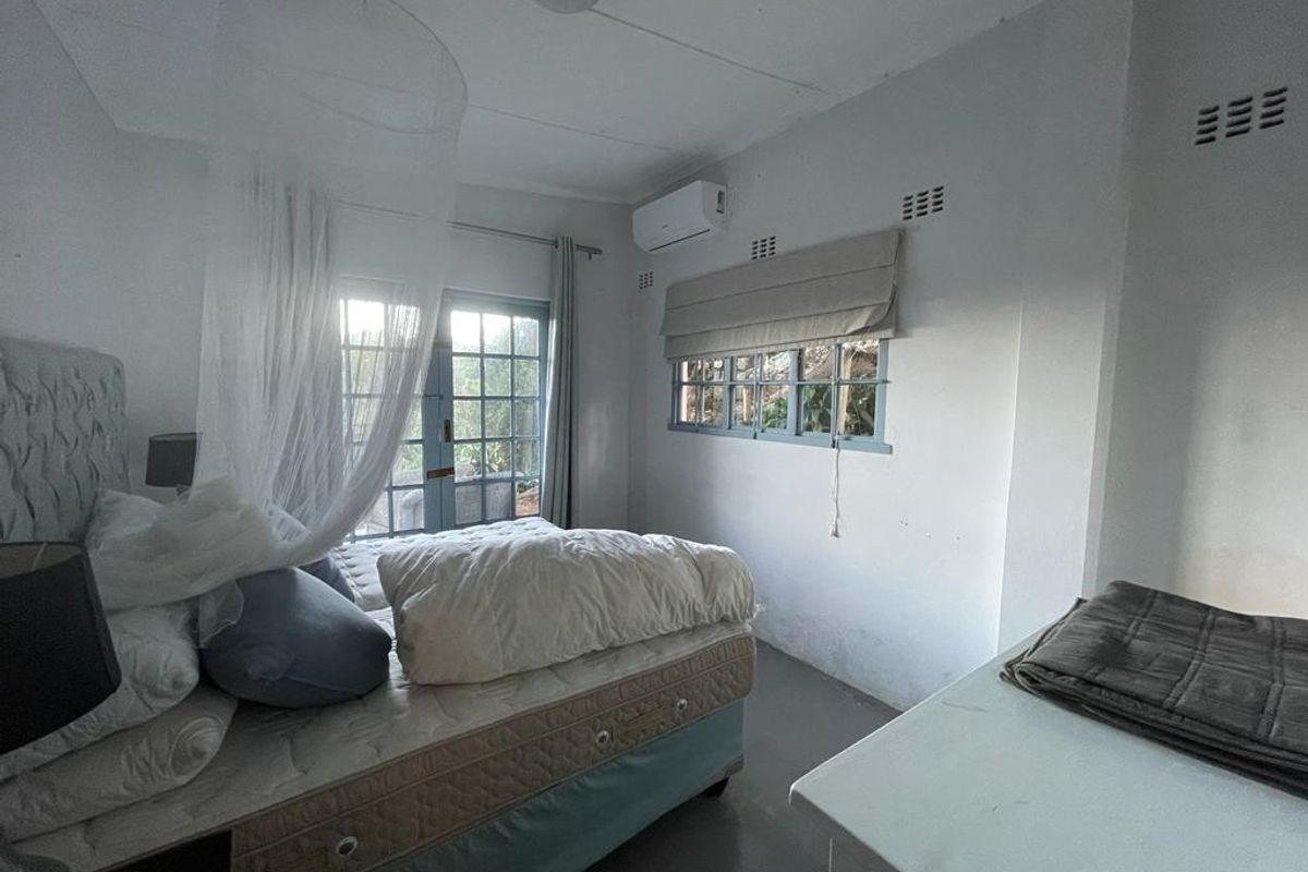 A bedroom featuring a split-system air conditioning unit, large glass doors leading outdoors, and multiple windows providing natural light.