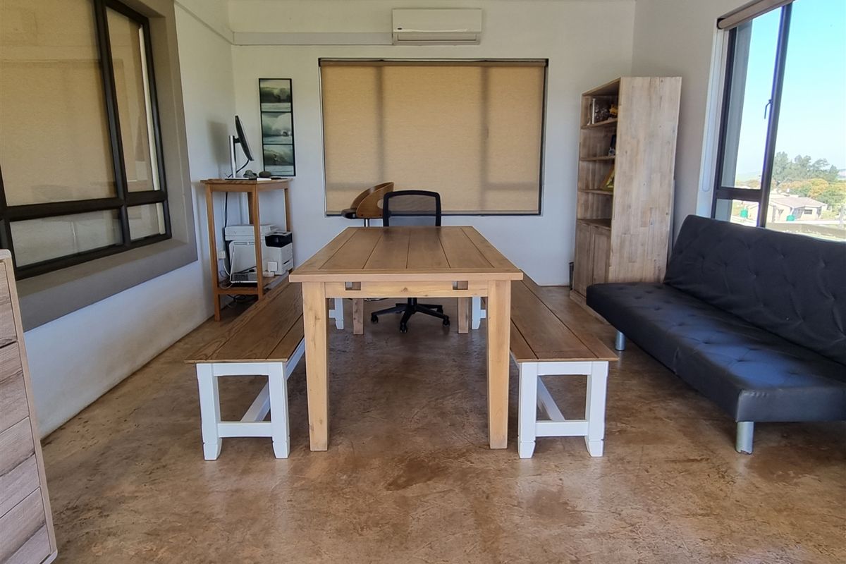A bright, multi-purpose room featuring polished concrete flooring, large windows, and a wall-mounted air conditioning unit.