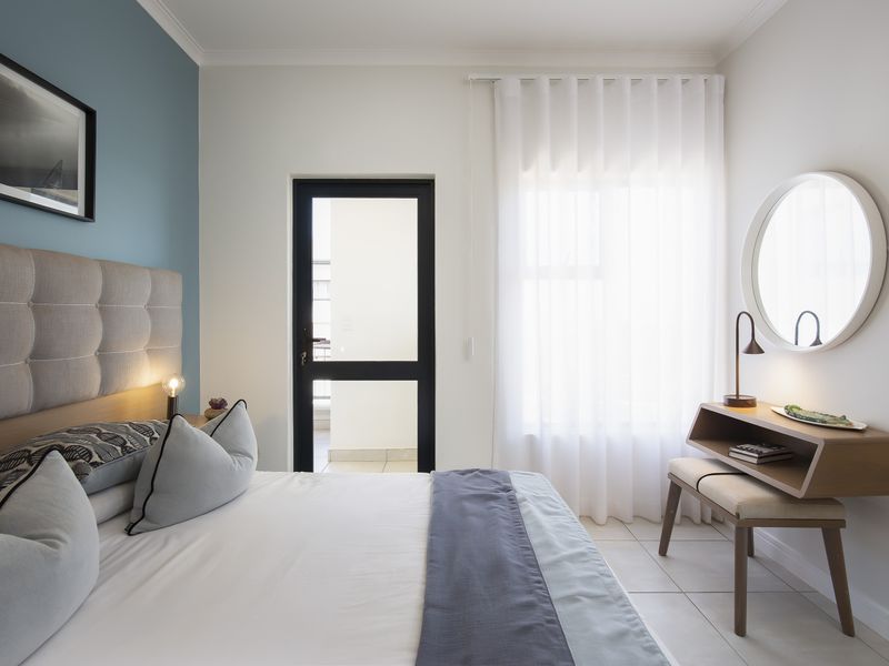 A well-maintained bedroom featuring tiled flooring, a feature wall, and a glass door providing access to an outdoor area.