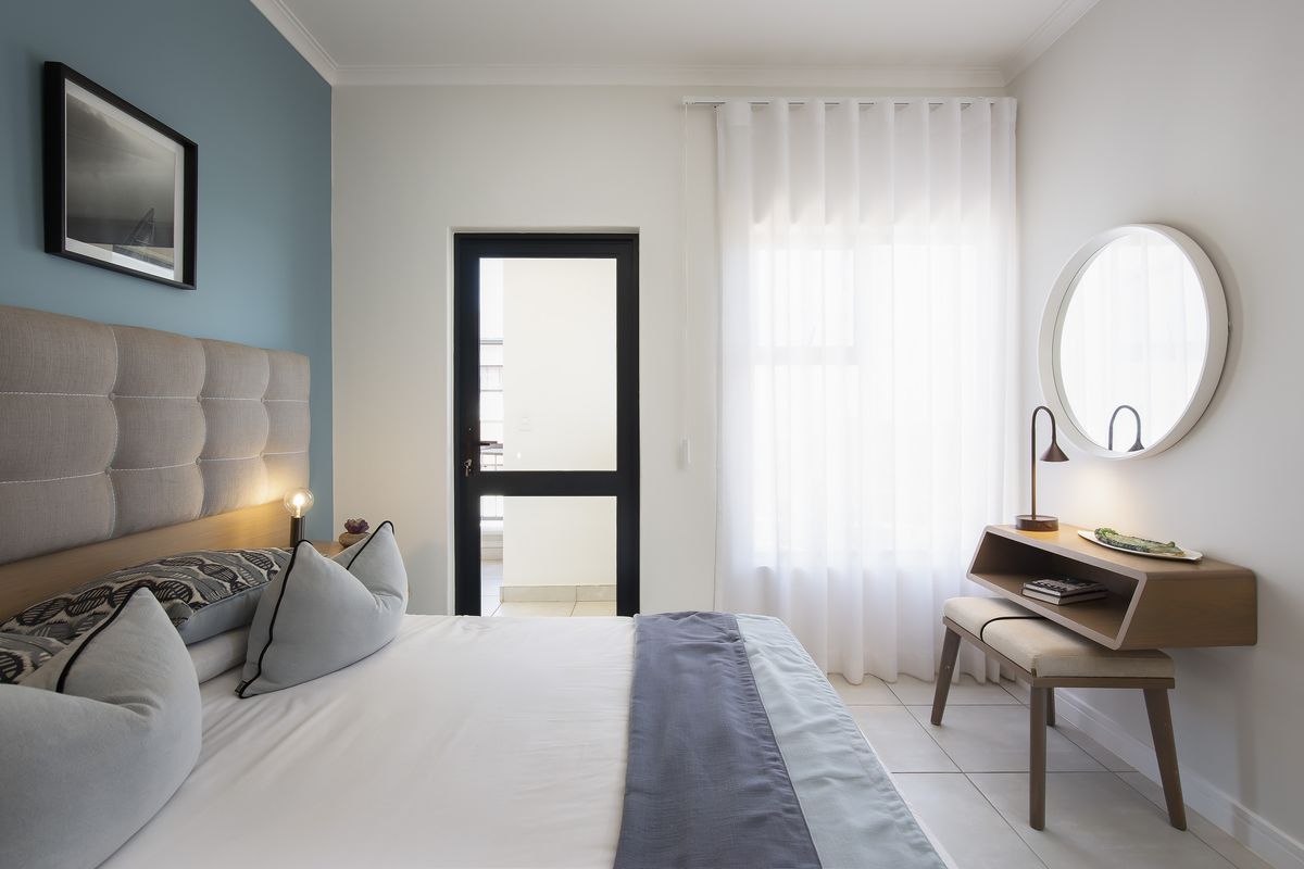 A well-maintained bedroom featuring tiled flooring, a feature wall, and a glass door providing access to an outdoor area.