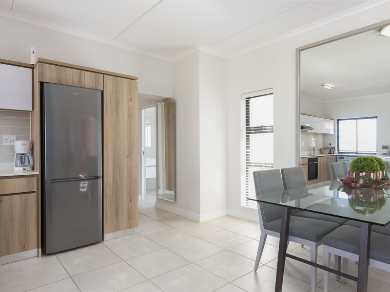 Modern open-plan living and kitchen area featuring light wood cabinetry, neutral tiled flooring, and a bright, functional layout.