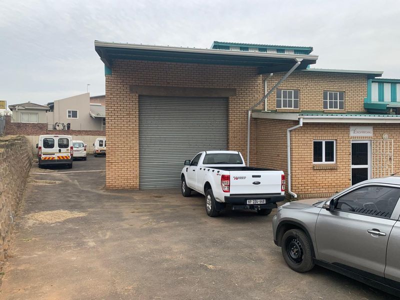 Industrial property exterior featuring a large roller shutter door, brick facade, and paved driveway access.