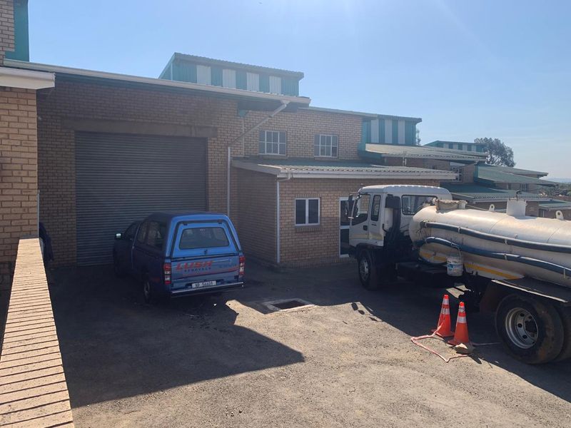 Industrial property exterior featuring a large roller shutter door, brick facade, and paved driveway access.