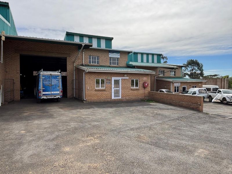 Front elevation of an industrial property featuring face brick construction, a large roller shutter door, and an asphalt parking area.