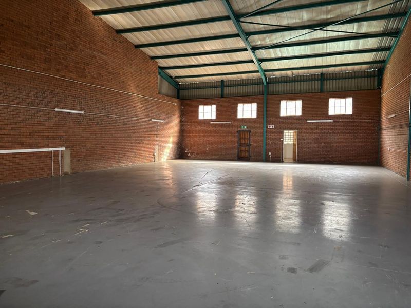 Spacious industrial warehouse unit featuring exposed brick walls, high-clearance steel portal frame, and durable concrete flooring with secure access points.