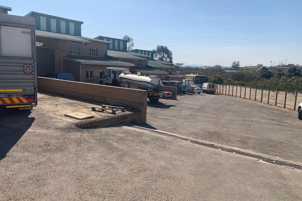 Industrial rear yard featuring a loading bay, asphalt surface, drainage infrastructure, and secure perimeter fencing, suitable for logistics or storage operations.