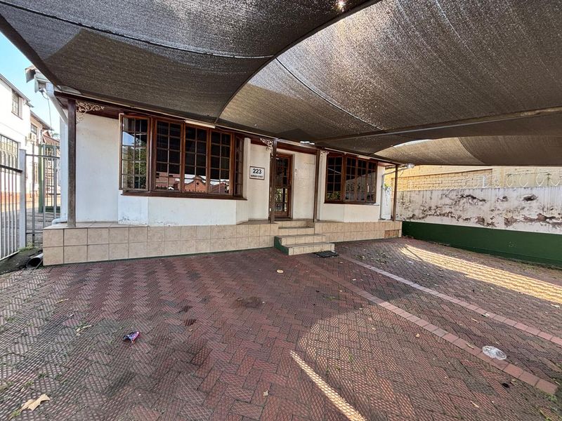Front exterior view of the office property featuring a paved driveway, covered parking area, and traditional timber-framed bay windows.