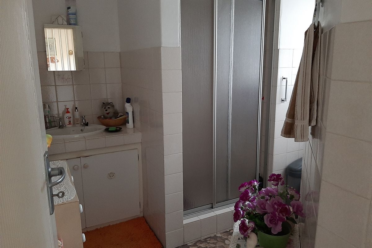 A functional bathroom featuring a vanity cabinet with integrated basin and a separate shower enclosure with sliding doors.