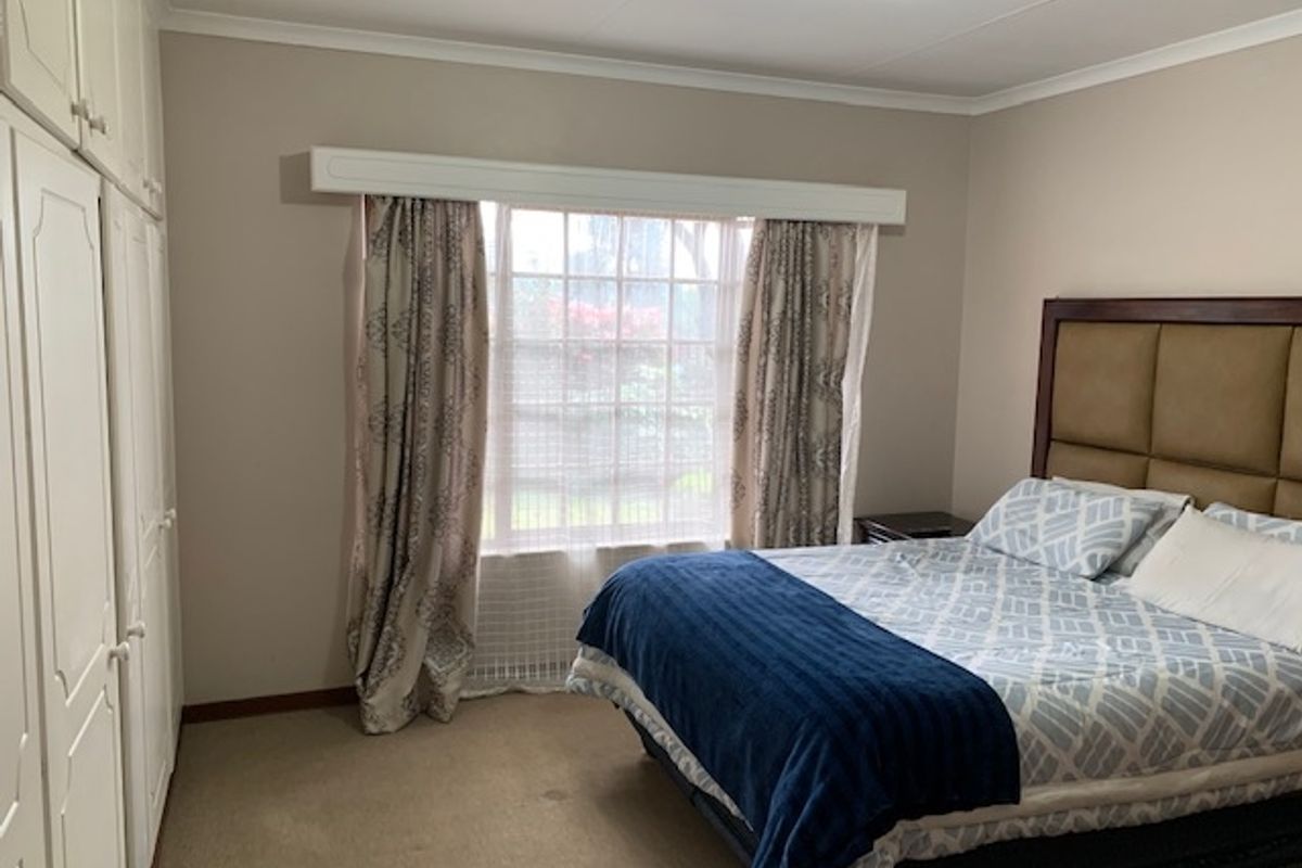 A bedroom featuring built-in cabinetry and a window with a pelmet, providing functional storage and natural light.