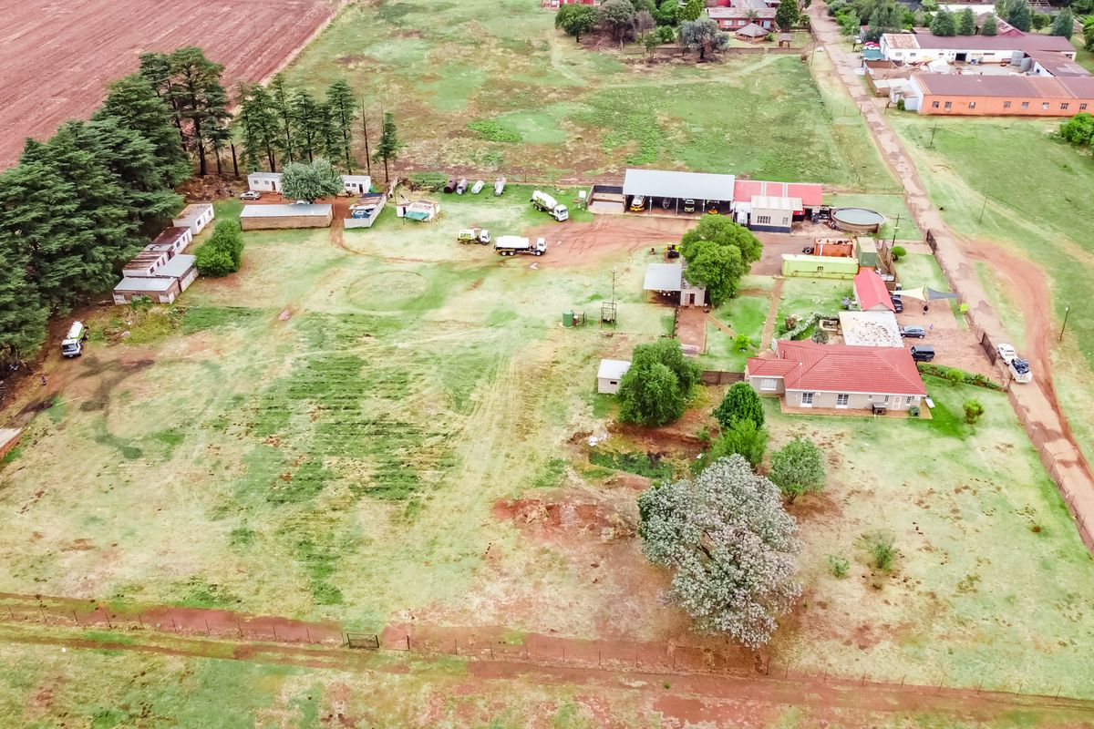Aerial view of a small holding property featuring a main residence, multiple outbuildings, workshop facilities, and expansive grounds.