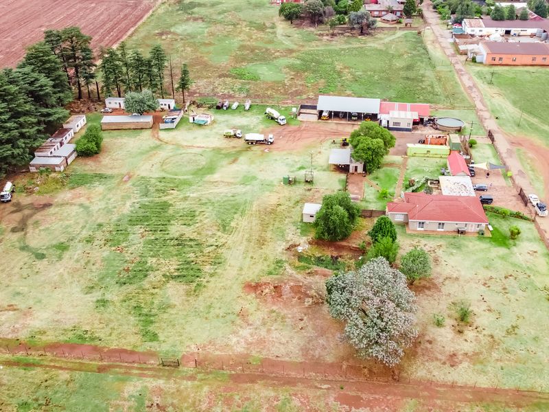 Aerial view of a small holding property featuring a main residence, multiple outbuildings, workshop facilities, and expansive grounds.