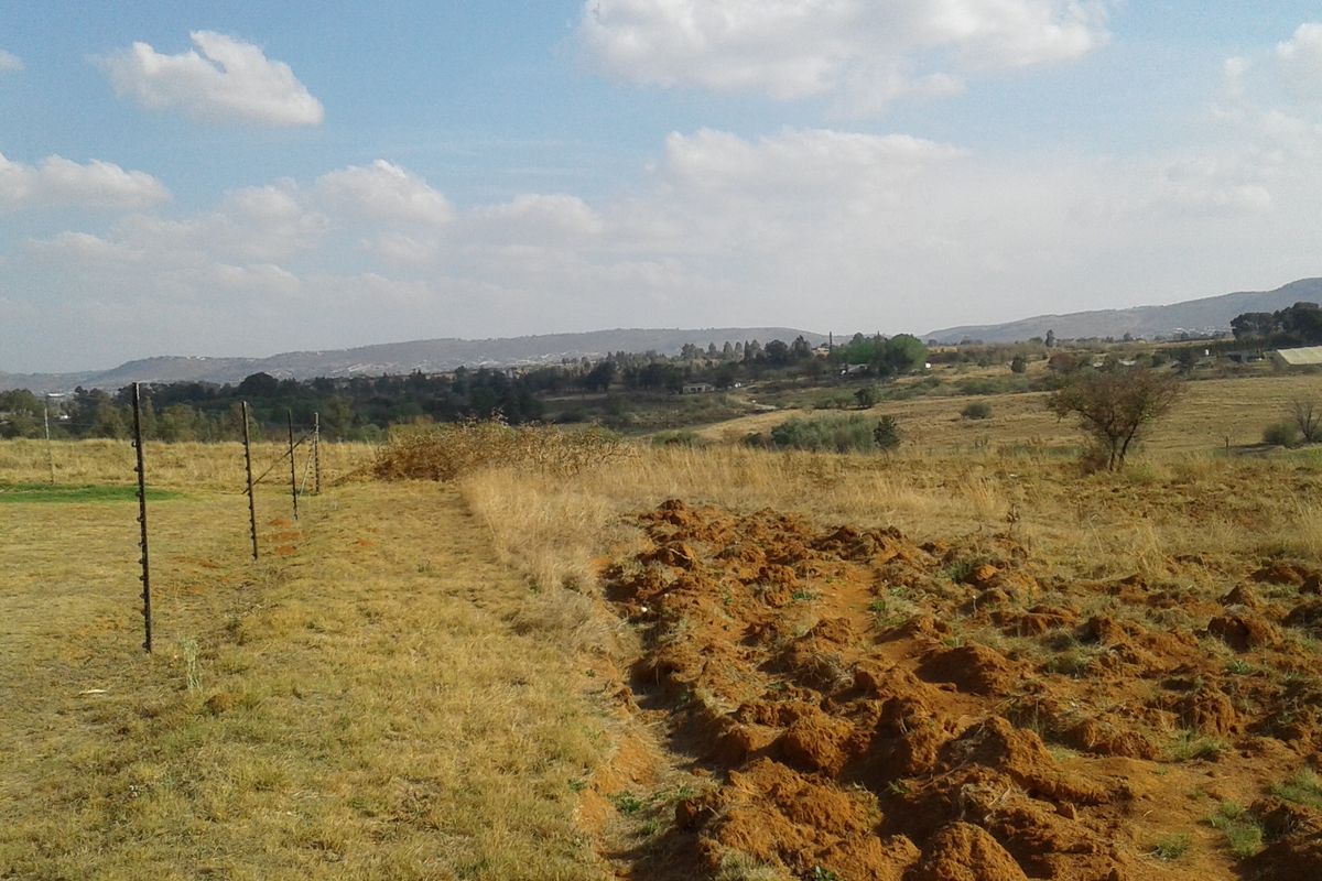 A view of the vacant commercial land featuring open fields, natural landscape, and perimeter electric fencing.