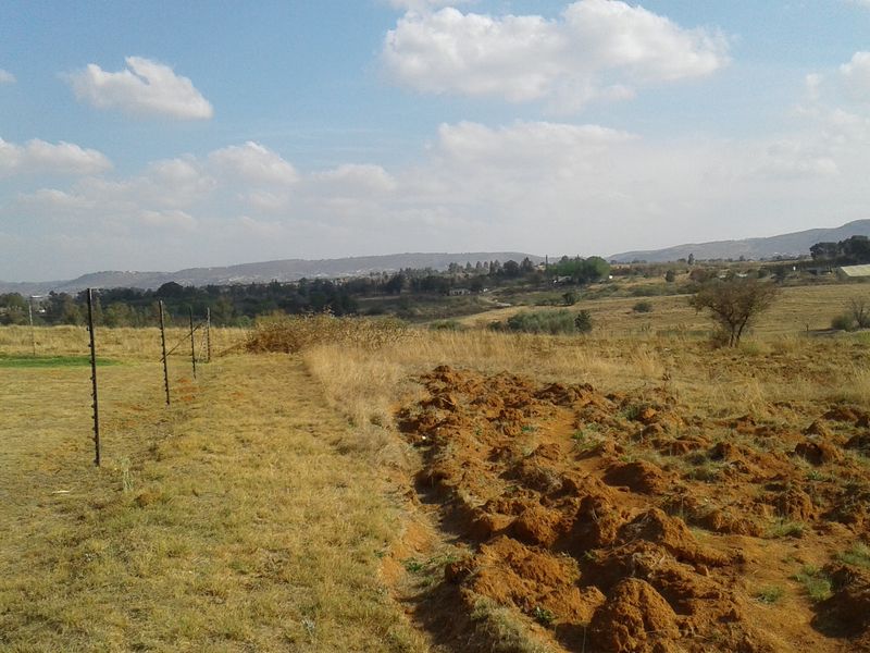 A view of the vacant commercial land featuring open fields, natural landscape, and perimeter electric fencing.