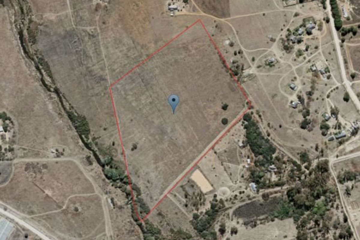 An aerial view of a large, vacant commercial land plot with a red boundary outline indicating the property perimeter.