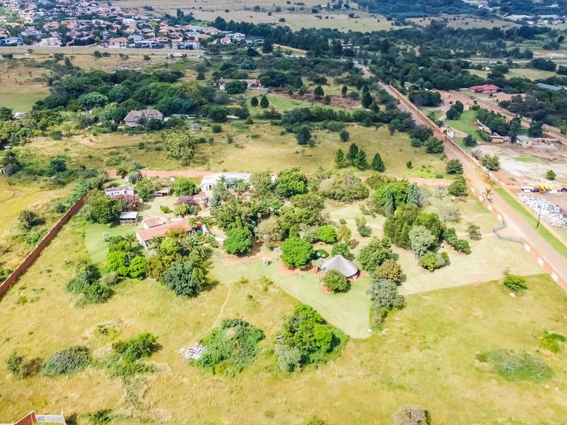 Aerial view of a large commercial vacant land plot featuring established trees, perimeter walling, and surrounding suburban infrastructure.