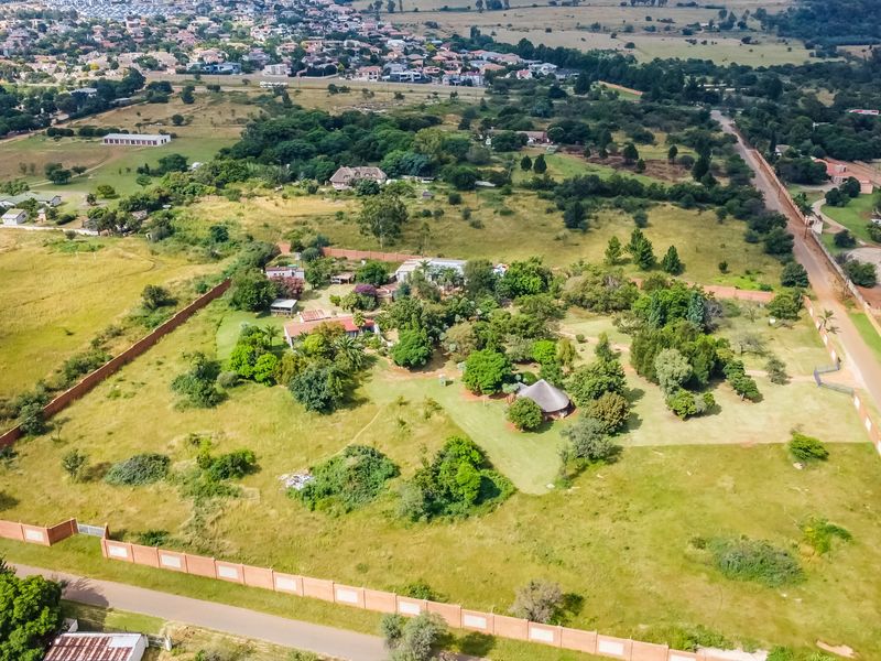 Aerial view of a large commercial vacant land plot featuring established trees, perimeter walling, and surrounding suburban infrastructure.