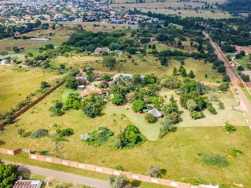 Aerial view of a large, undeveloped commercial land parcel featuring perimeter walling, mature trees, and surrounding residential infrastructure.