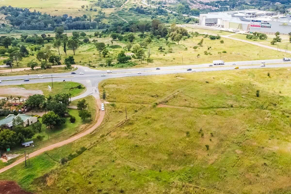 Aerial view of a large, undeveloped commercial land parcel situated near a major road intersection and established commercial facilities.