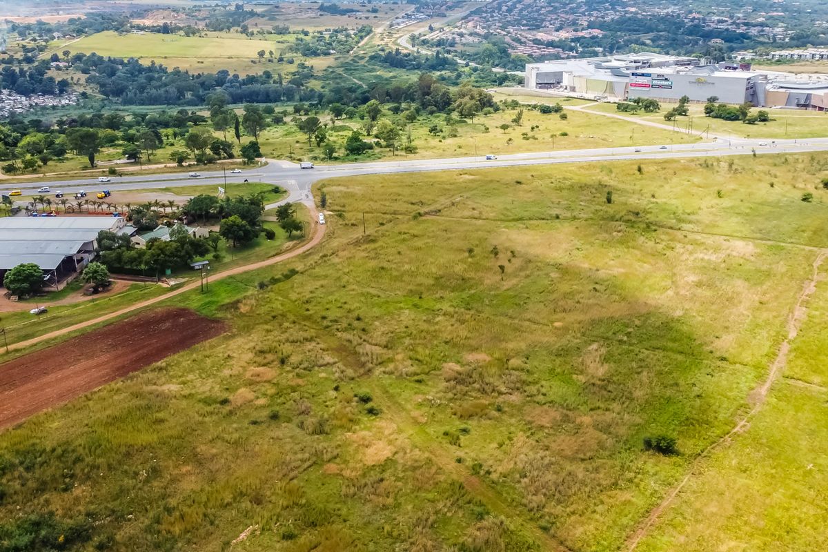 Aerial view of a large, undeveloped commercial land parcel situated near a major road and existing commercial infrastructure.