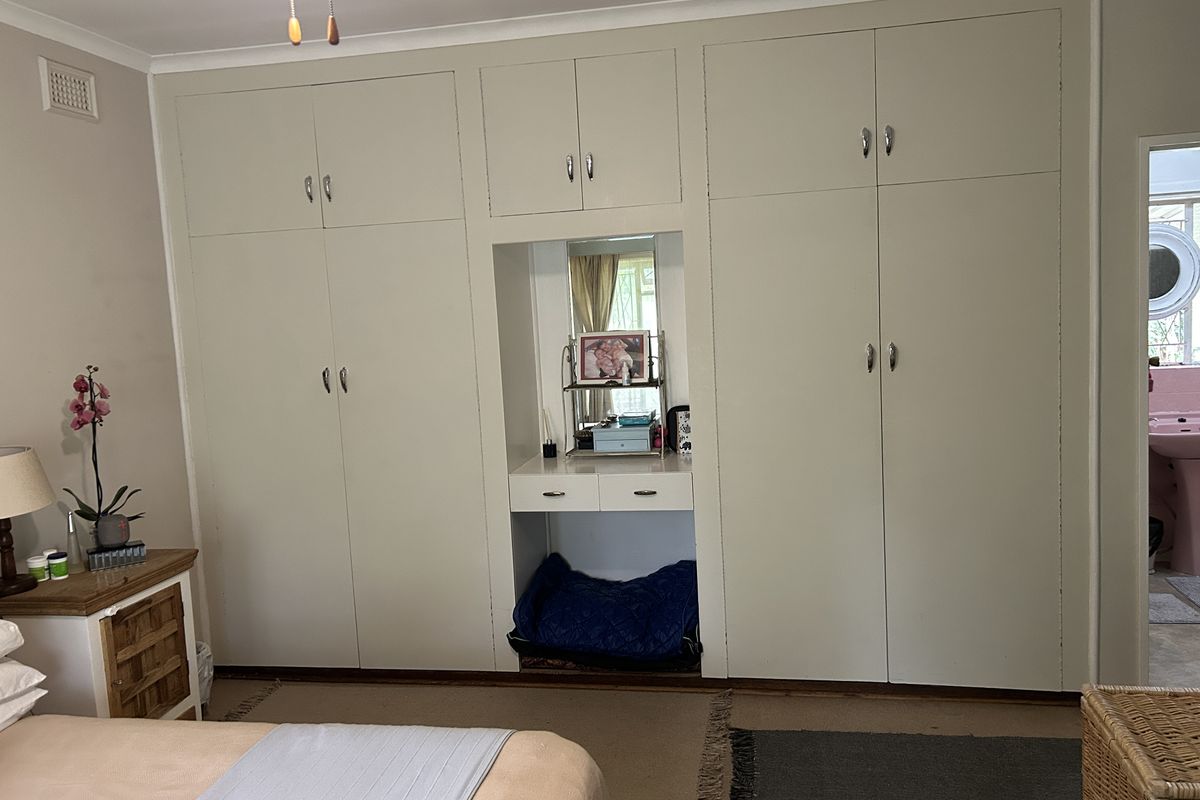 A bedroom featuring extensive floor-to-ceiling built-in cabinetry with a central integrated vanity and mirror, providing ample storage space.