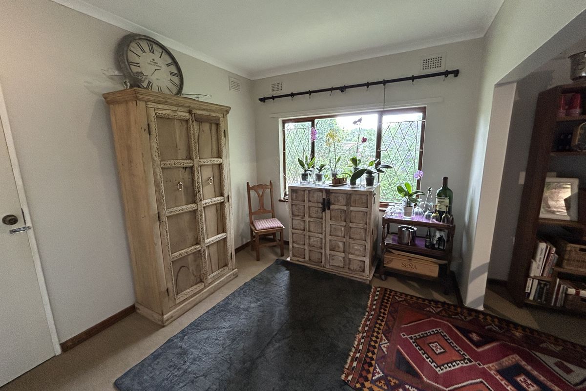 A cozy living area featuring leaded glass windows, neutral wall finishes, and carpeted flooring, providing a comfortable and well-lit space.