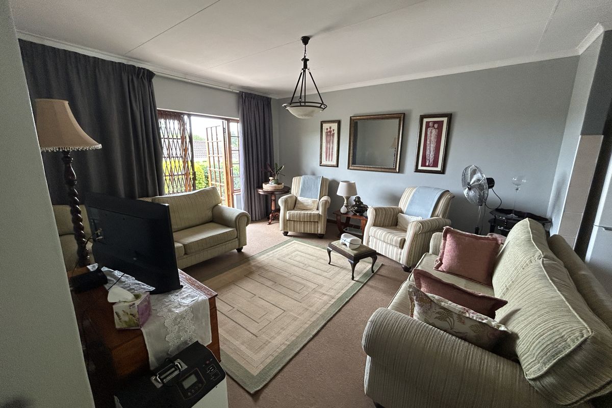 A spacious living room featuring neutral wall tones, carpeted flooring, and direct access to the outdoor area through a sliding glass door.