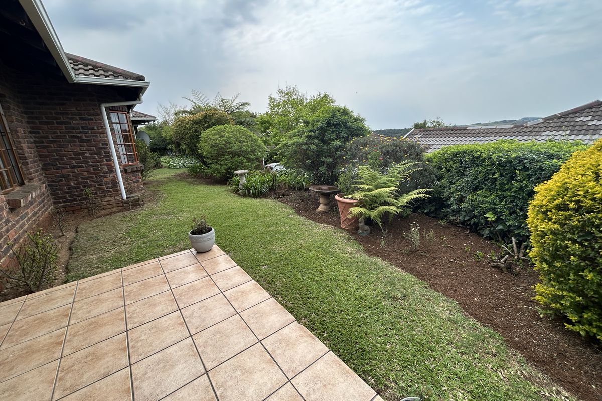 A well-maintained rear garden featuring a tiled patio area, established landscaping, and classic brick townhouse architecture.