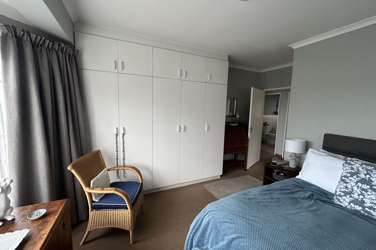 A bedroom featuring extensive built-in white cabinetry, neutral wall tones, and direct access to an adjoining bathroom.