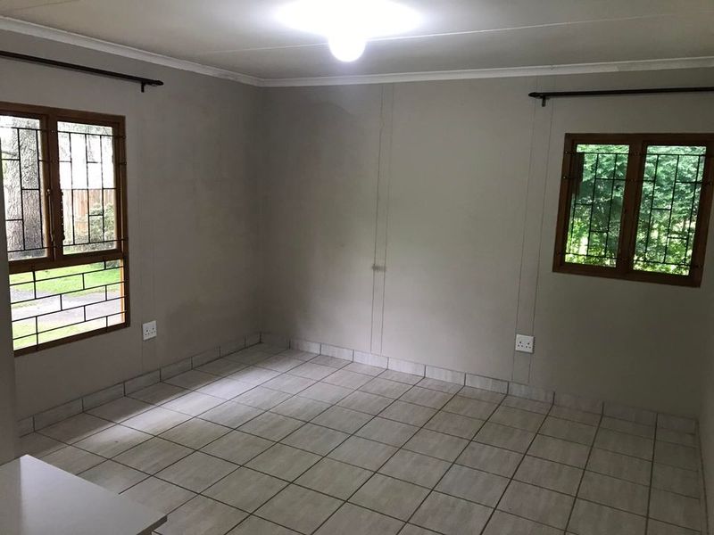An empty bedroom featuring tiled flooring, security bars on the windows, and neutral wall finishes, providing a blank canvas for personalization.