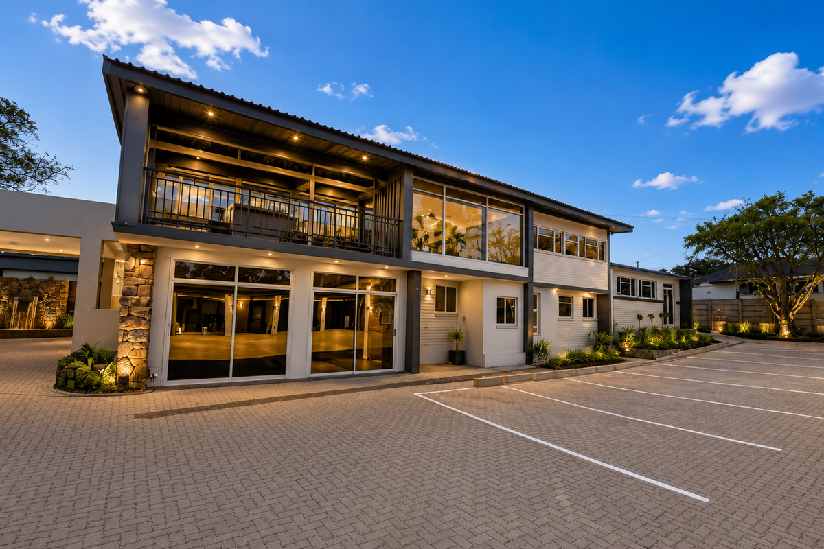 Modern office building exterior featuring a paved parking area, stone-clad accents, a spacious balcony, and integrated architectural lighting.