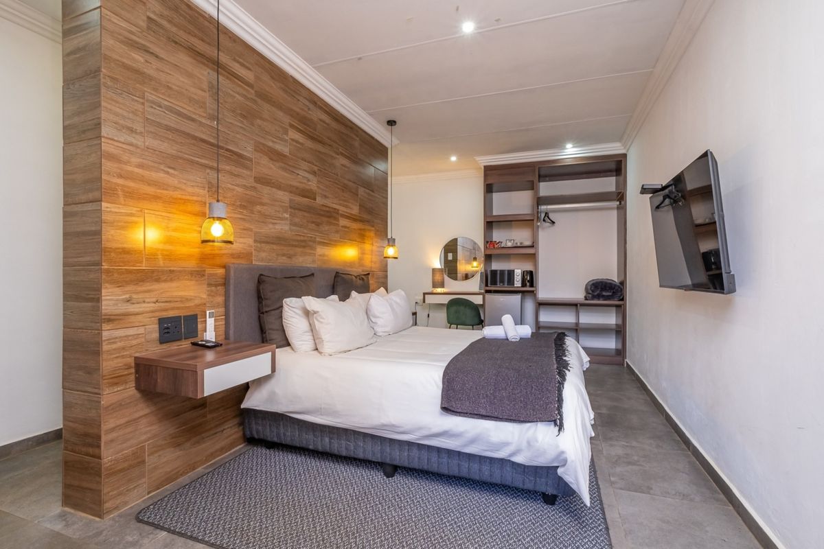 Modern bedroom featuring a wood-look feature wall, built-in open wardrobe, wall-mounted bedside tables, and contemporary pendant lighting.