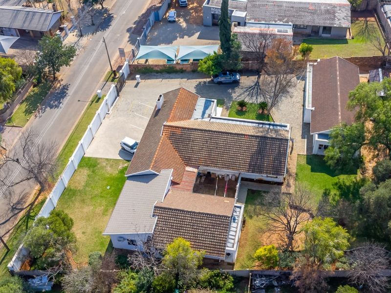 Aerial view of the guest house property, showcasing the building layout, tiled roofing, paved driveway, and surrounding garden area.