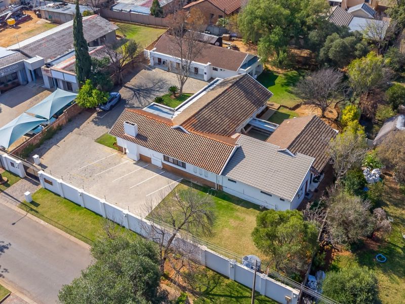 Aerial view of the guest house property showing the main building, paved parking area, perimeter wall, and surrounding grounds.
