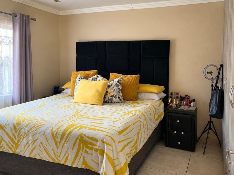 A bedroom featuring tiled flooring, a built-in wardrobe, and a window fitted with a security gate.