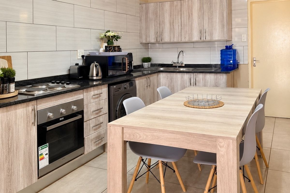 Modern kitchen featuring light wood-grain cabinetry, granite countertops, built-in oven and hob, and tiled finishes throughout.