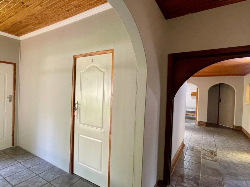 A spacious hallway featuring tiled flooring, timber ceilings, and multiple arched doorways leading to various rooms within the apartment.