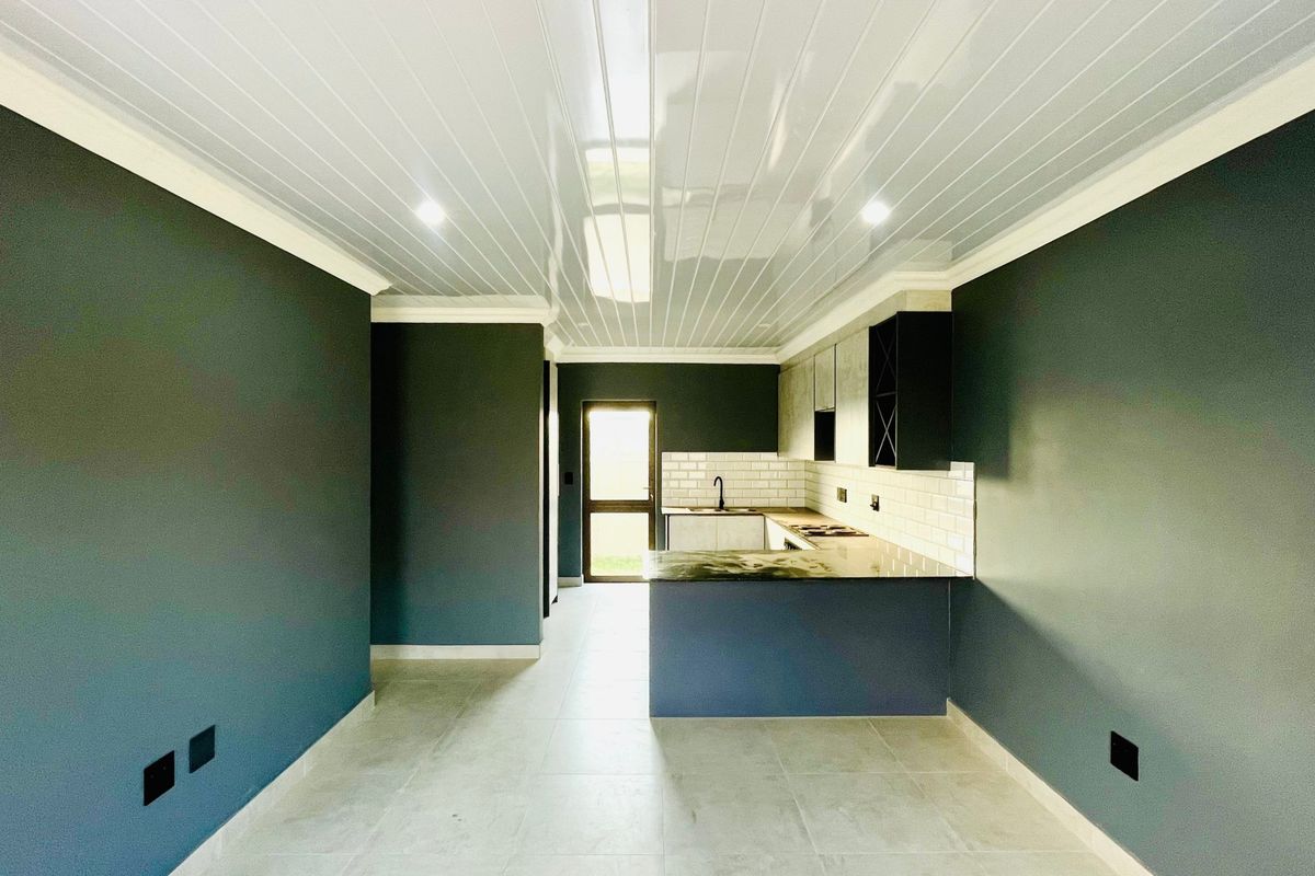 A modern, empty kitchen featuring dark cabinetry, a subway tile backsplash, stone countertops, and a clean, minimalist aesthetic with recessed lighting.