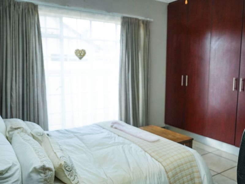 A bedroom featuring dark wood built-in cupboards and tiled flooring, offering a functional space with natural light.