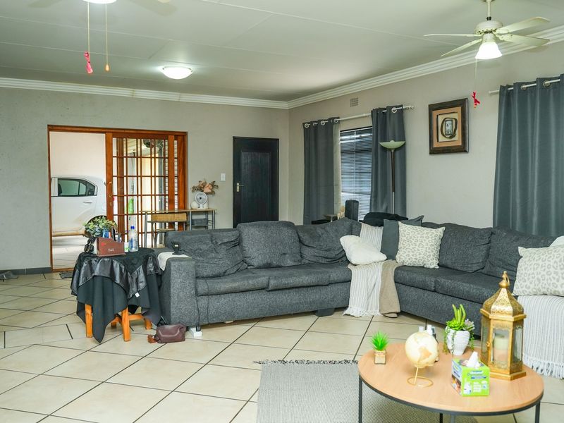 Spacious living area featuring tiled flooring, ceiling fans, and direct access to an adjacent space through a sliding door.